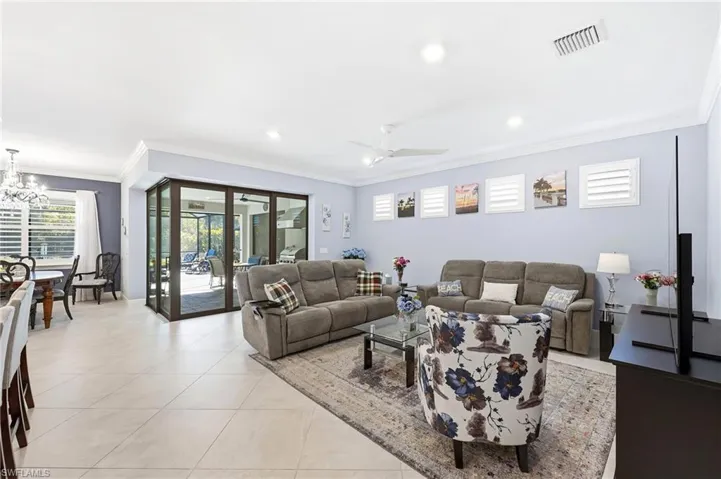 Living room featuring ornamental molding, healthy amount of natural light, light tile patterned floors, a ceiling fan, and suspended lighting