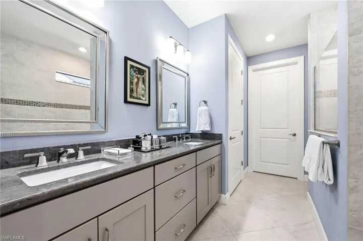 Full bath with double vanity, light tile patterned flooring, recessed lighting, and a tile shower