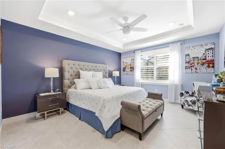 Bedroom featuring ornamental molding, ceiling fan, a raised ceiling, and light tile patterned flooring