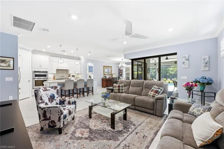 Living area with ornamental molding, hanging lights, and light tile patterned floors