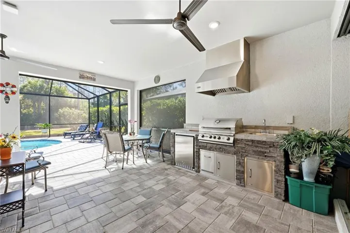 View of patio / terrace featuring a lanai, ceiling fan, an outdoor kitchen / dining area, a sunroom, and an outdoor pool
