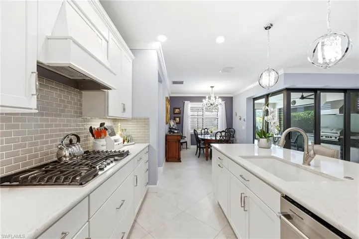 Kitchen featuring white cabinetry, light stone counters, stainless steel appliances, and ornamental molding