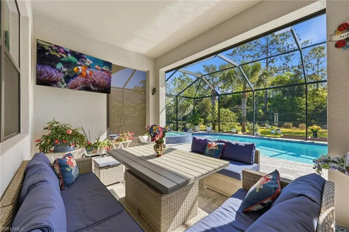 View of patio / terrace with glass enclosure, a sunroom, a pool with connected hot tub, and outdoor lounge area