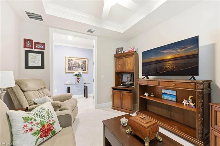 Living area featuring ornamental molding, a raised ceiling, a ceiling fan, and light tile patterned flooring