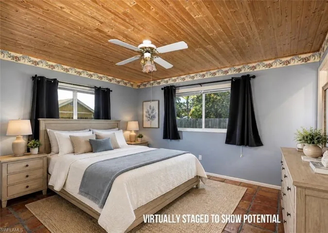 VIRTUALLY STAGED  Wood-paneled ceiling with ceiling fan, multiple windows with dark drapery, light blue painted walls, and terracotta-style flooring