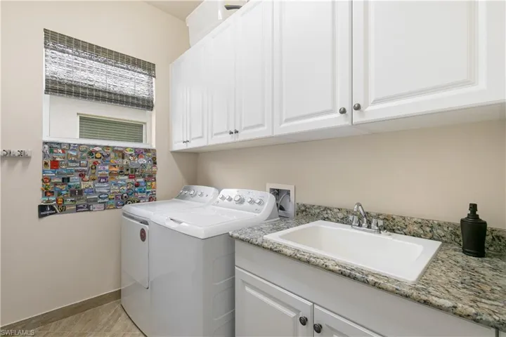 Laundry room featuring washing machine and clothes dryer, cabinet space, and baseboards