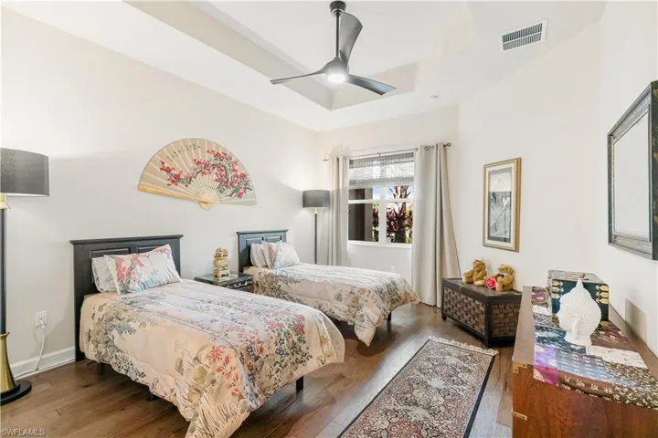 Bedroom featuring wood finished floors, a ceiling fan, baseboards, and a raised ceiling
