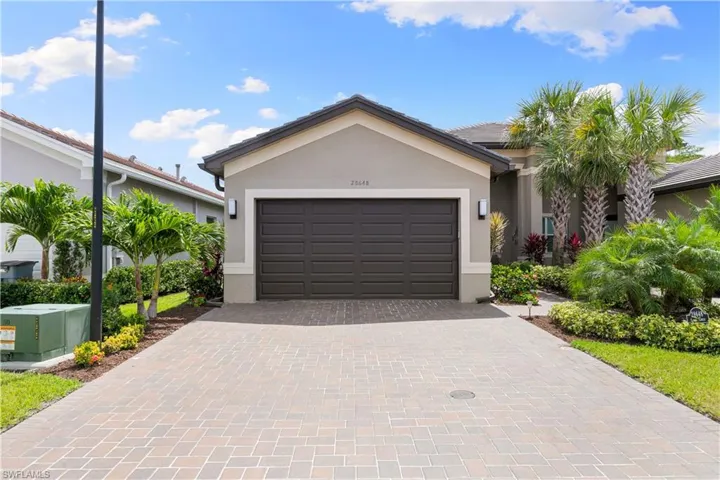 Single story home featuring stucco siding, decorative driveway, and a garage