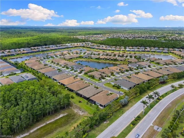 Aerial view of property's location featuring nearby suburban area, a nearby body of water, and a forest