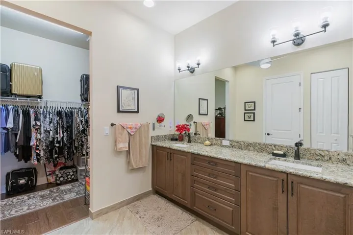 Full bathroom featuring double vanity, baseboards, and a spacious closet