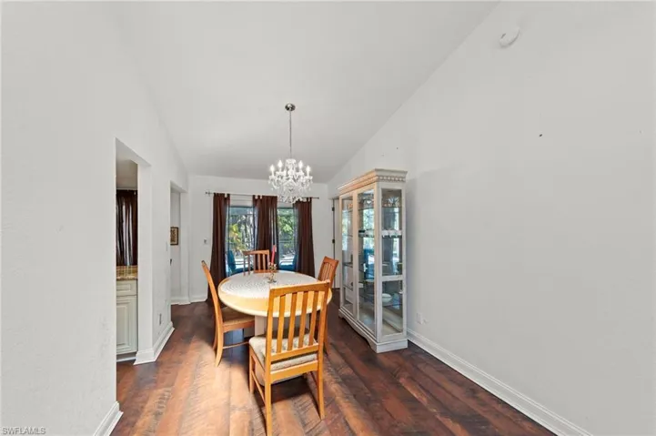 Dining room with hanging lights, dark wood-style floors, and lofted ceiling