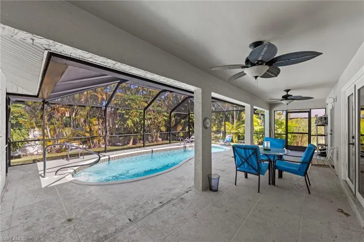 Outdoor pool featuring a patio area, a sunroom, glass enclosure, and outdoor dining space