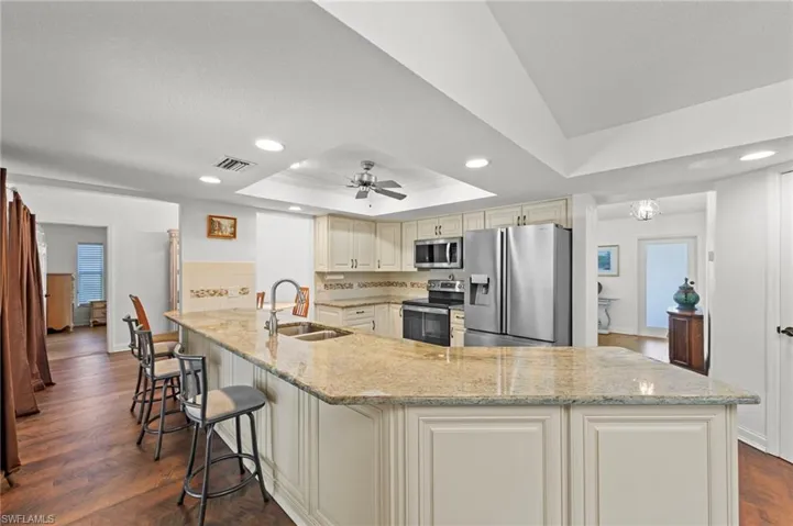 Kitchen featuring recessed lighting, stainless steel appliances, ceiling fan, dark wood-style flooring, and light stone countertops