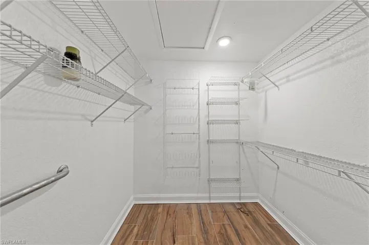 Walk in closet with dark wood-type flooring