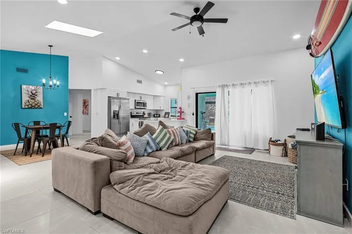 Living area with a chandelier, ceiling fan, recessed lighting, a skylight, and high vaulted ceiling