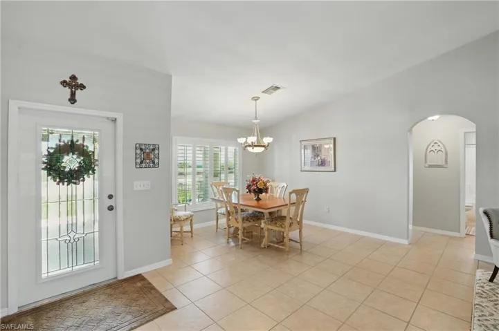 Dining space featuring arched walkways, a chandelier, light tile patterned floors, and baseboards