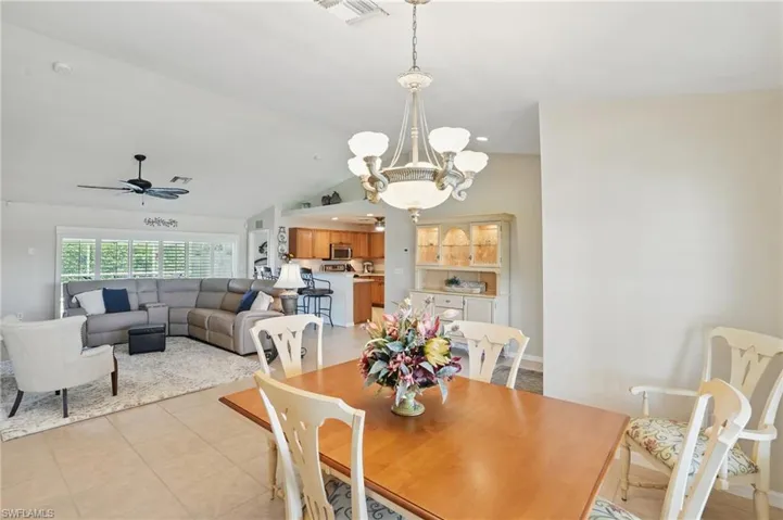 Dining area featuring light tile patterned floors, a chandelier, a ceiling fan, and lofted ceiling