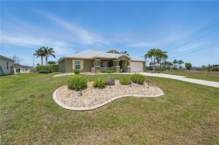 Ranch-style house featuring an attached garage, driveway, a front yard, stucco siding, and covered porch