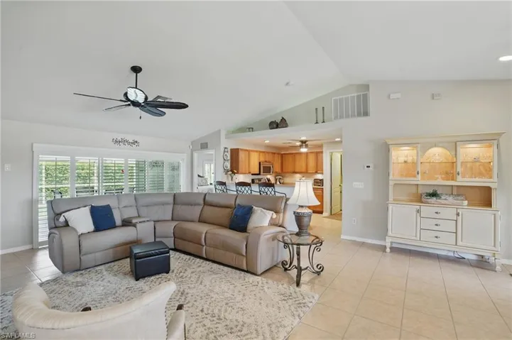 Living room with ceiling fan, light tile patterned flooring, baseboards, and high vaulted ceiling