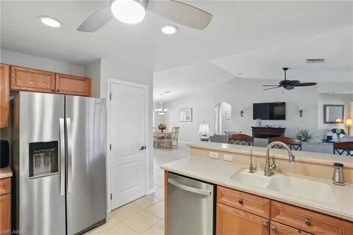 Kitchen with stainless steel appliances, a ceiling fan, open floor plan, a sink, and light tile patterned flooring