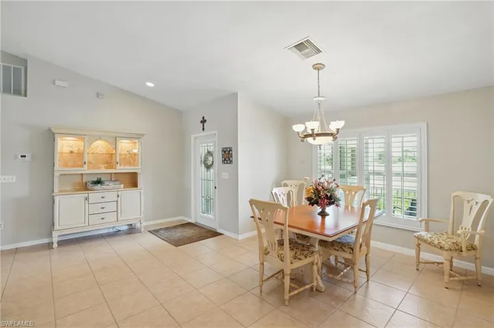 Dining area with a chandelier, light tile patterned floors, baseboards, and lofted ceiling
