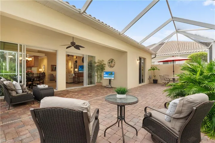 Screened-in lanai featuring paver flooring, a ceiling fan, and large multi-panel sliding glass doors