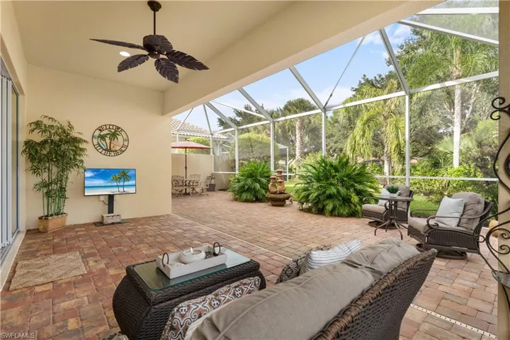 Screened lanai featuring brick paver flooring and a ceiling fan with palm-leaf blades