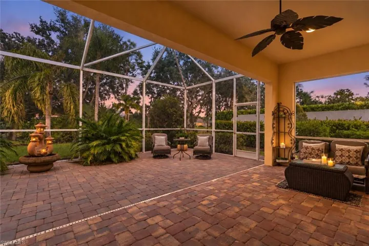 Covered lanai featuring paver flooring, a screened enclosure, and a ceiling-mounted fan