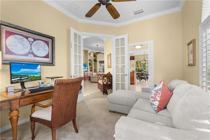 Interior room featuring tray ceilings with crown molding, double French doors with glass panes, plantation shutters, and a ceiling fan