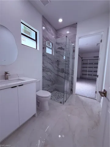 Contemporary bathroom featuring a spacious glass-enclosed shower with marble-look tile surround and a tiled shower pan