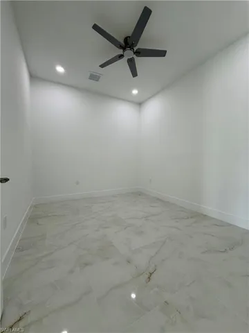 Room featuring large format porcelain tile flooring with a subtle veining pattern, white baseboards, and crisp white walls