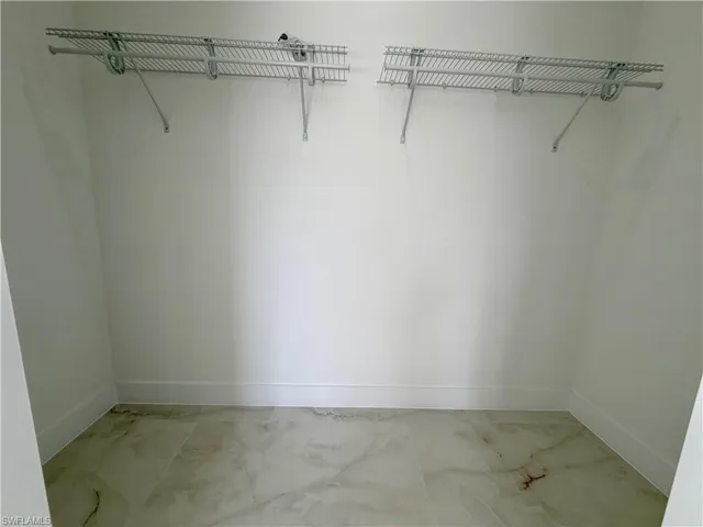 Walk-in closet featuring light-toned flooring, white walls, and two wire shelving units