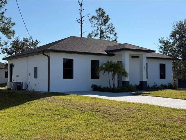 View of front of house featuring a front yard, stucco siding, and roof with shingles