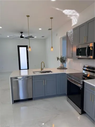 Kitchen with stainless steel range oven, a peninsula, dishwasher, light stone counters, and recessed lighting