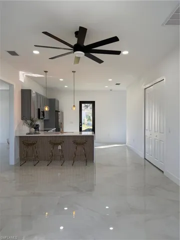 Kitchen featuring gray cabinetry, pendant lighting, a kitchen breakfast bar, recessed lighting, and open floor plan