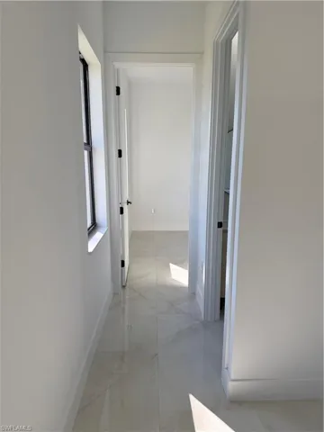 Corridor featuring baseboards and light marble finish floors