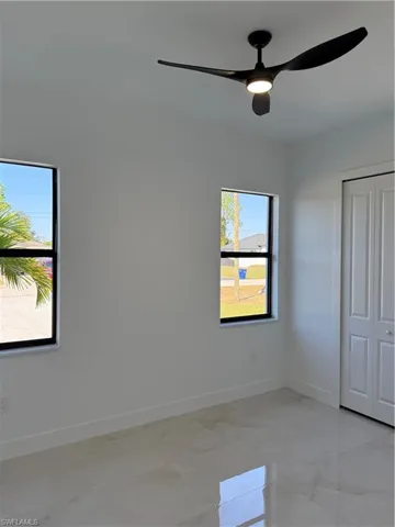 Unfurnished bedroom with light marble finish floors, ceiling fan, and a closet