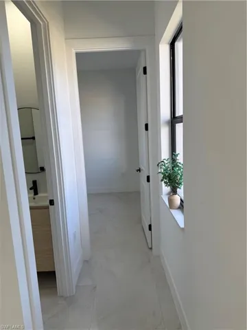 Hallway with baseboards and light marble finish floors