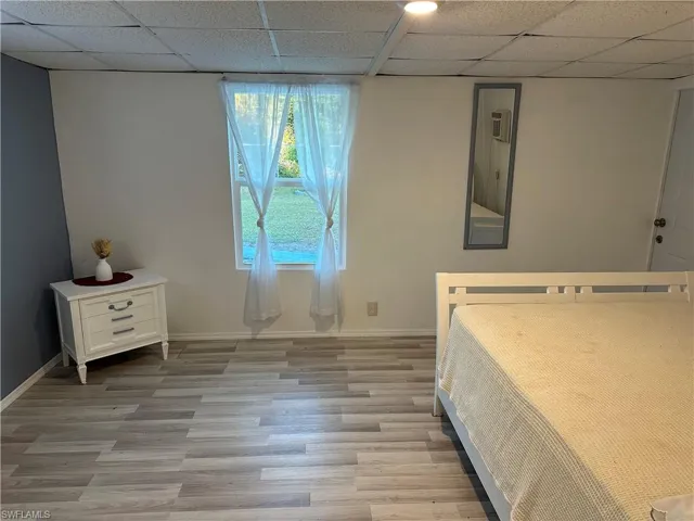 Unfurnished bedroom with light wood-type flooring and a drop ceiling