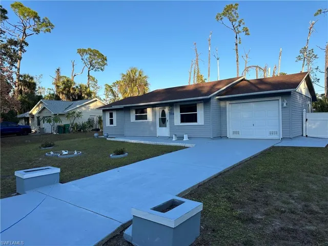 Single story home featuring driveway, a front lawn, and an attached garage