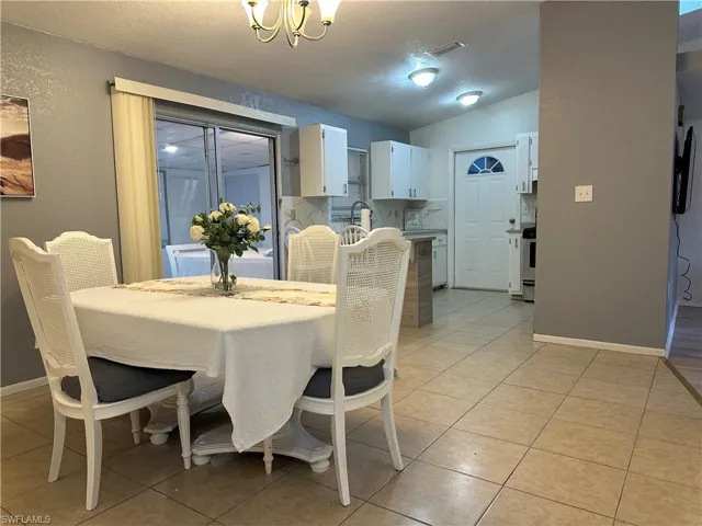 Dining room with a textured wall, a chandelier, and light tile patterned floors
