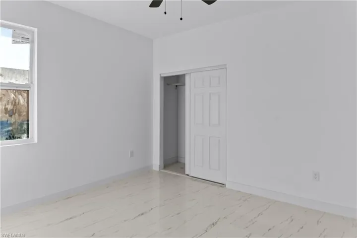 Unfurnished bedroom with ceiling fan, a closet, and multiple windows