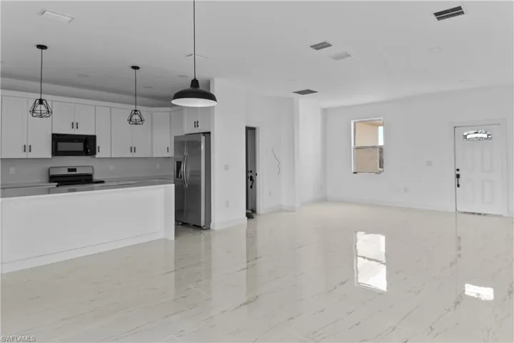 Kitchen with stainless steel appliances, white cabinets, and hanging light fixtures
