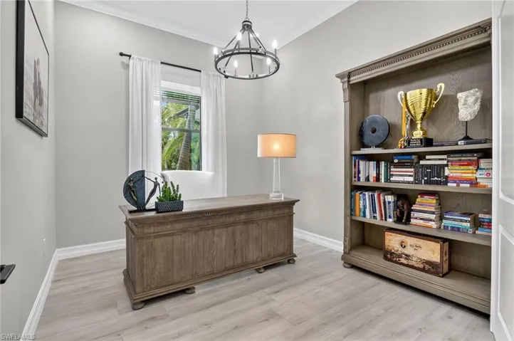 Office with crown molding, suspended lighting, and light wood-type flooring
