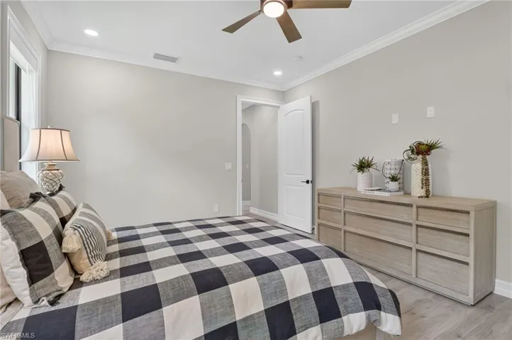 Bedroom featuring ornamental molding, a ceiling fan, recessed lighting, arched walkways, and light wood finished floors