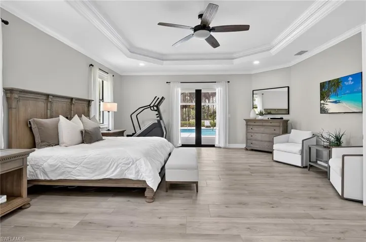Bedroom featuring light wood-style flooring, crown molding, ceiling fan, access to outside, and a tray ceiling