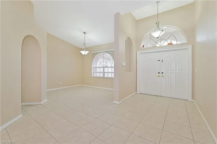 Foyer entrance featuring light tile patterned floors and vaulted ceiling