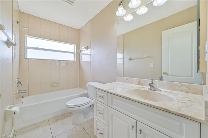 Full bathroom featuring tile patterned flooring, toilet, vanity, and tiled shower / bath