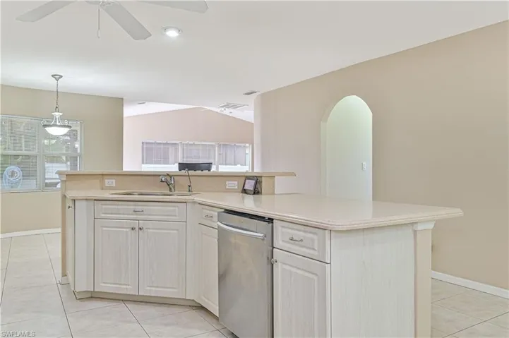 Kitchen with light tile patterned floors, dishwasher, ceiling fan, decorative light fixtures, and sink