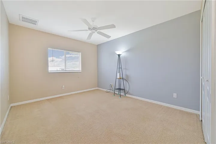 Empty room with light colored carpet and ceiling fan